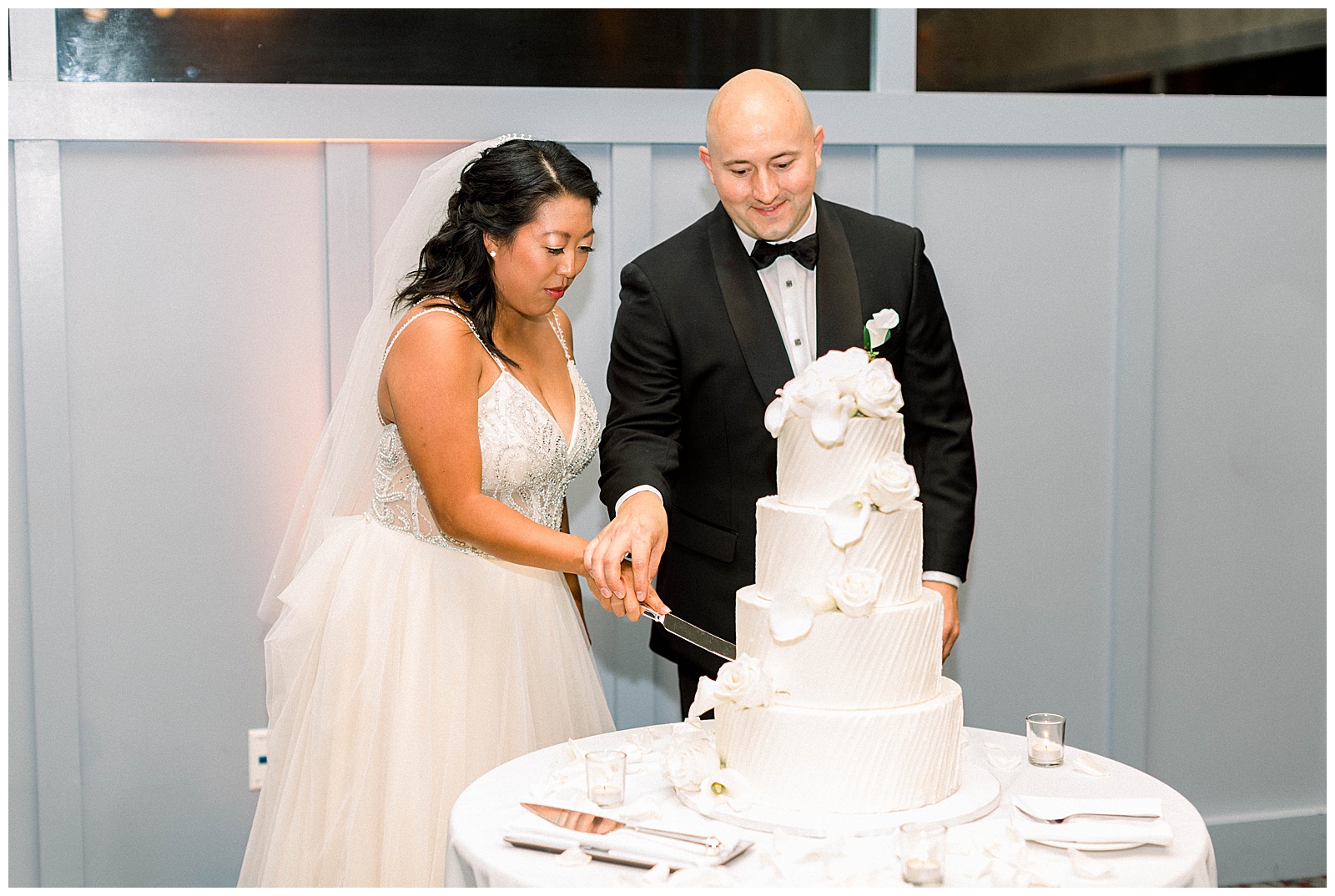 bride and groom cut white floral wedding cake